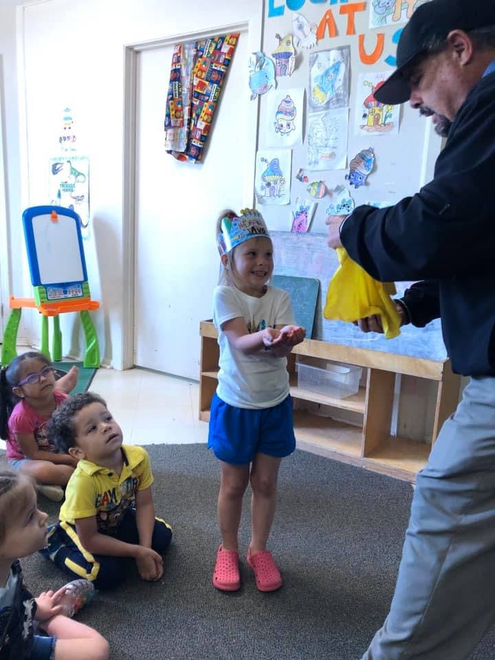 Adult holding yellow fabric for a child with other children watching