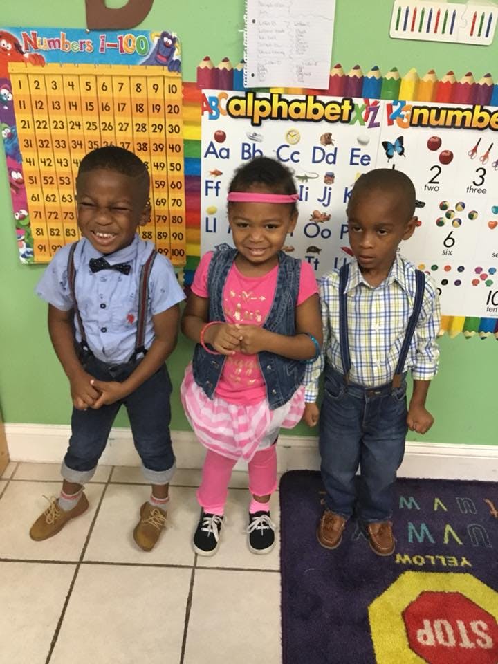 Three children standing in a classroom