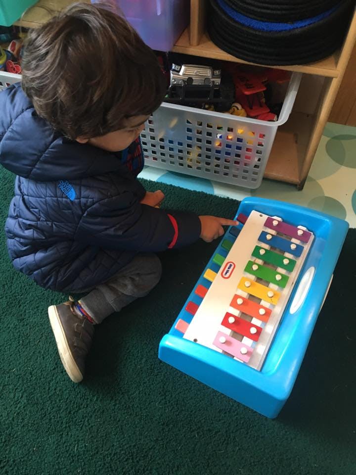 Child playing with a colorful toy xylophone