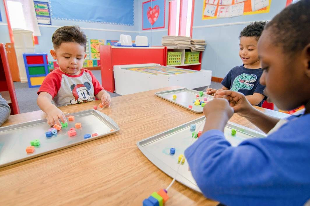 Children playing with colorful blocks at a table in a classroom