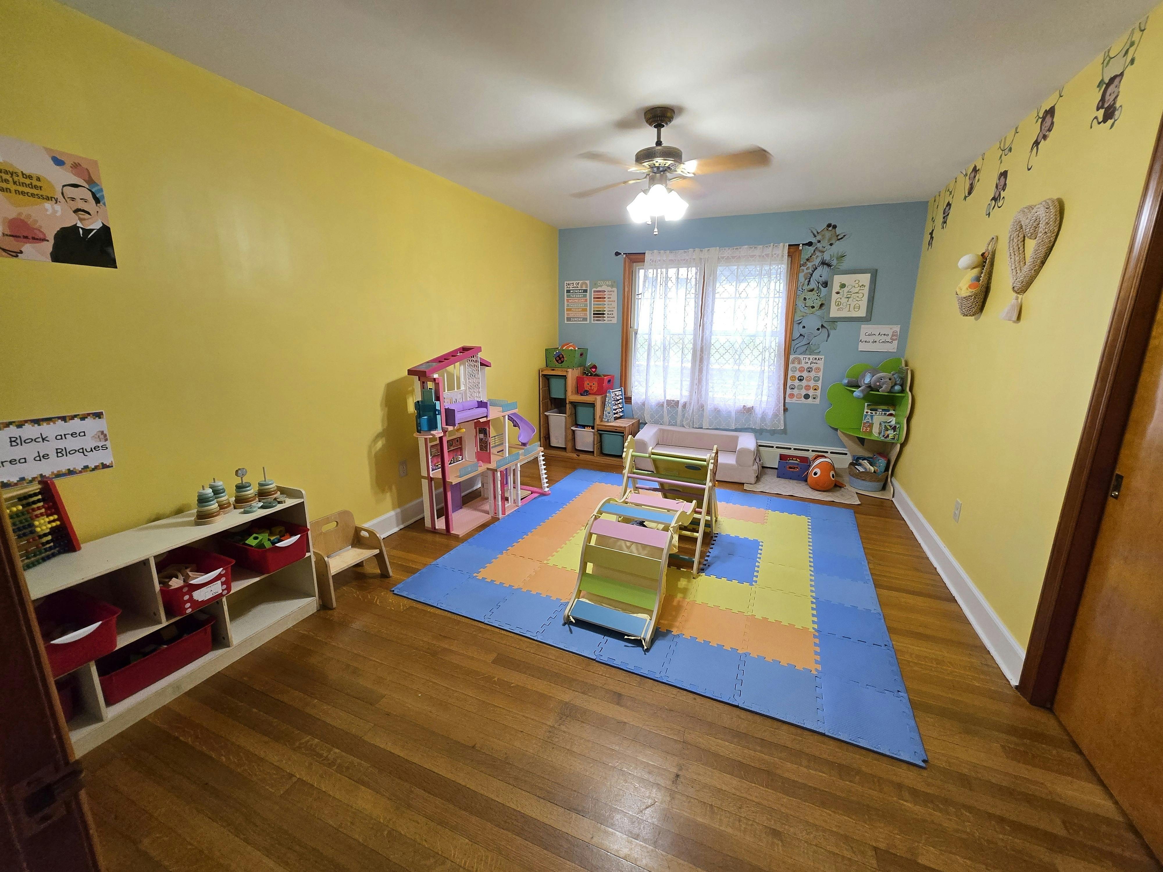 Playroom with yellow and blue walls, colorful rug, and toys