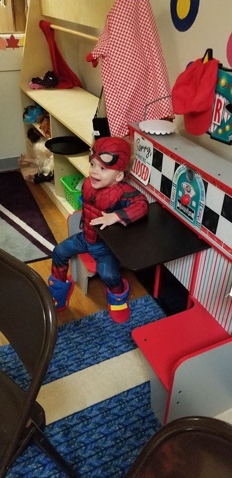 Child in a Spider-Man costume sitting at a play diner counter