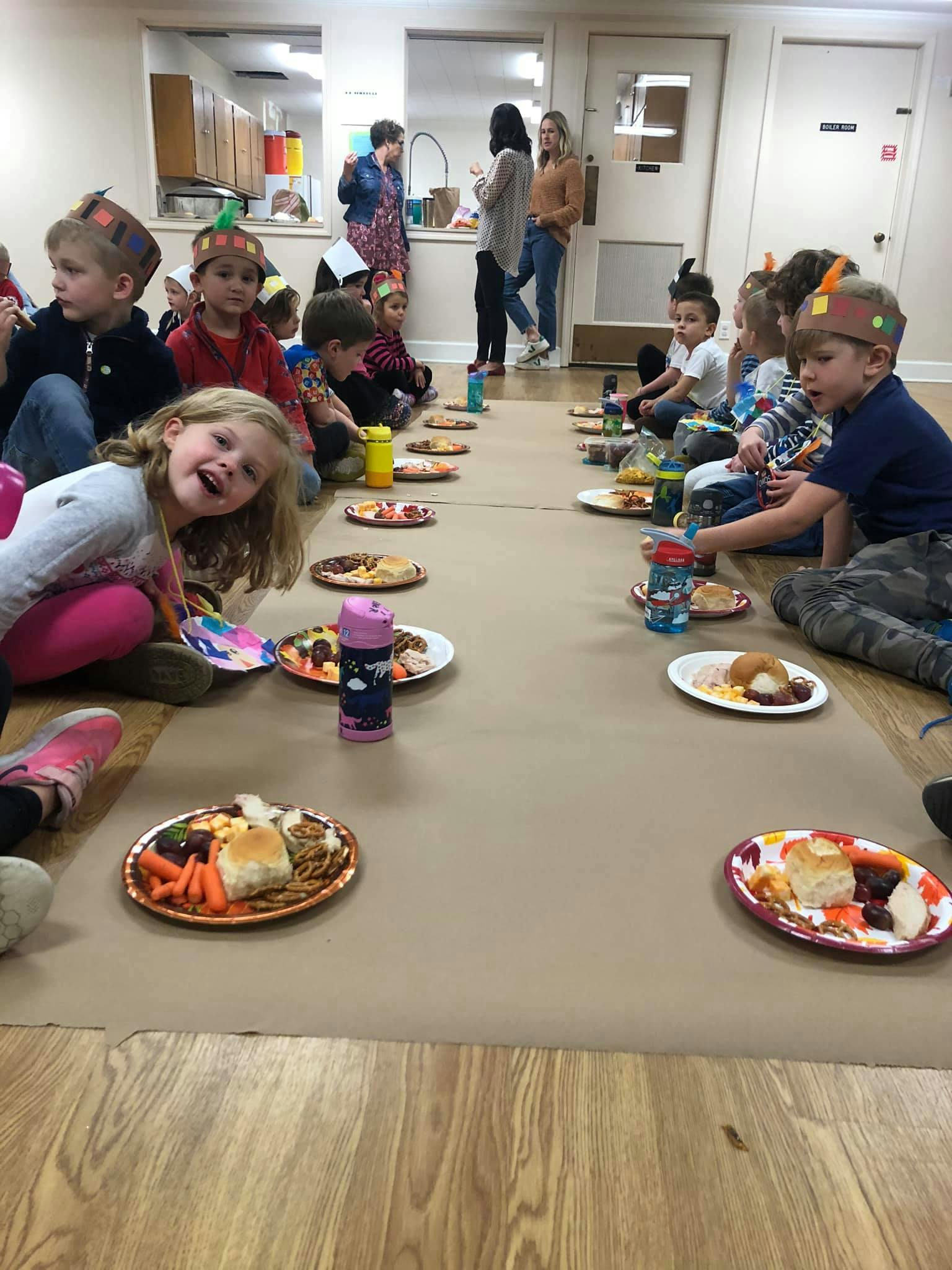 Children sitting on the floor with plates of food in front of them