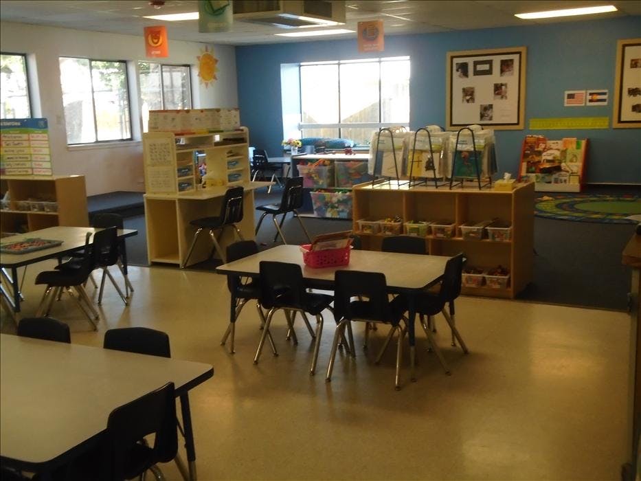 Empty classroom with small tables, chairs, and shelves