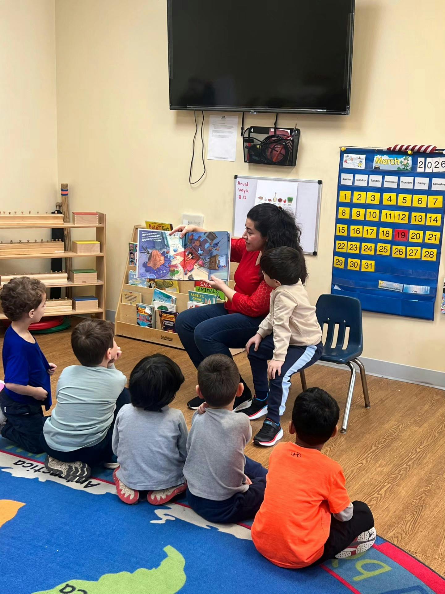 Adult reading a book to several children in a classroom
