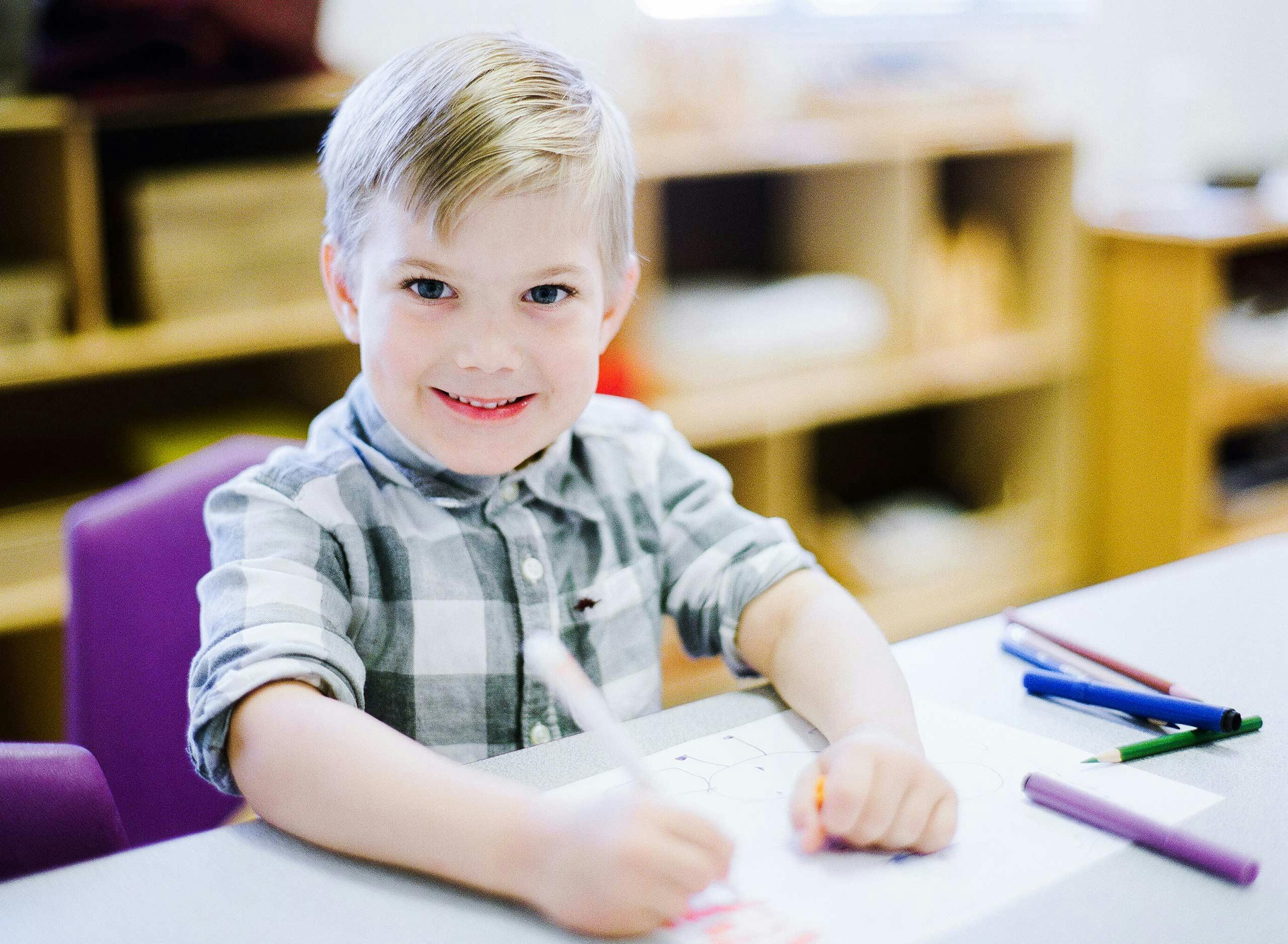 Child drawing at a table in a classroom