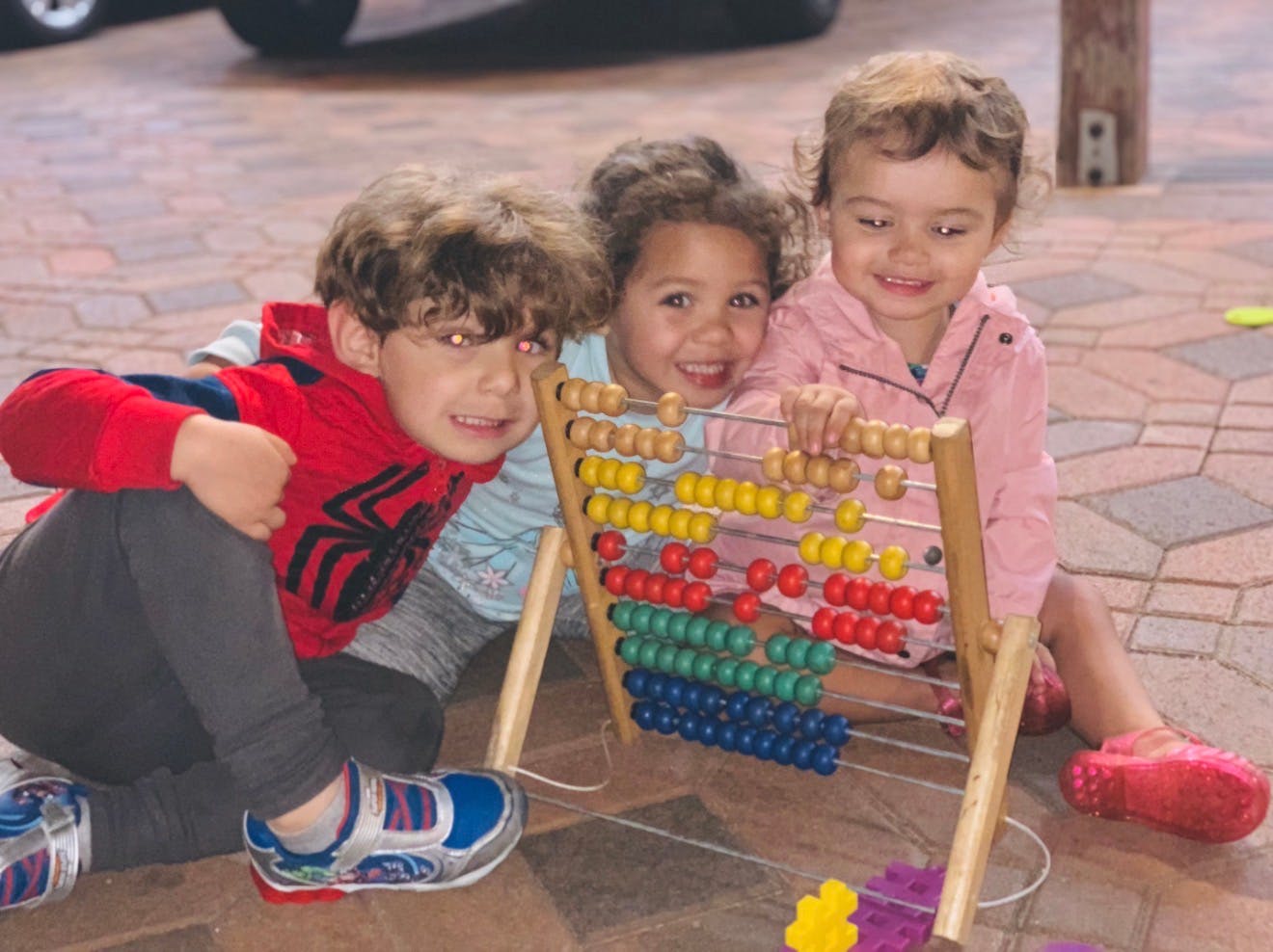 Three children playing with an abacus