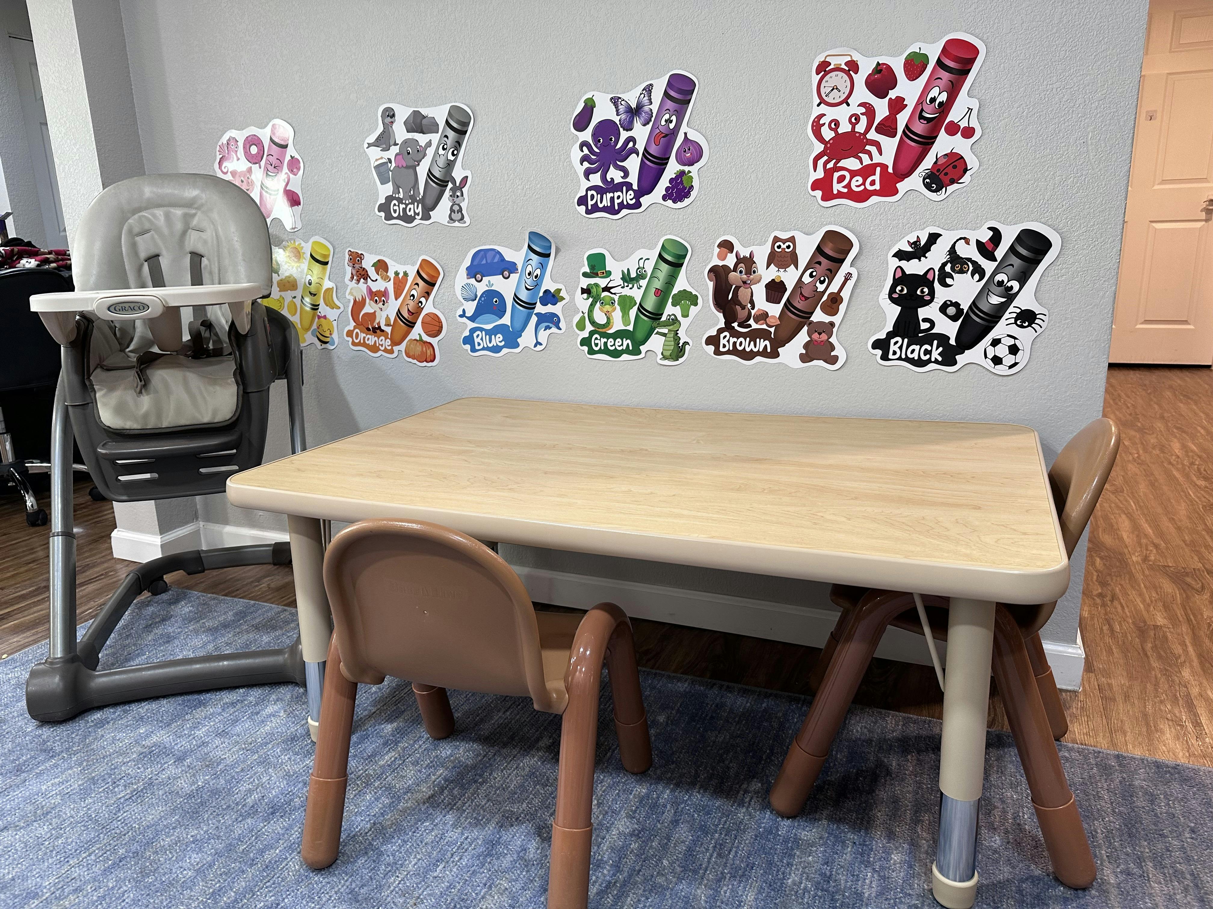 Crayon color cutouts on a wall above a child's table and chairs