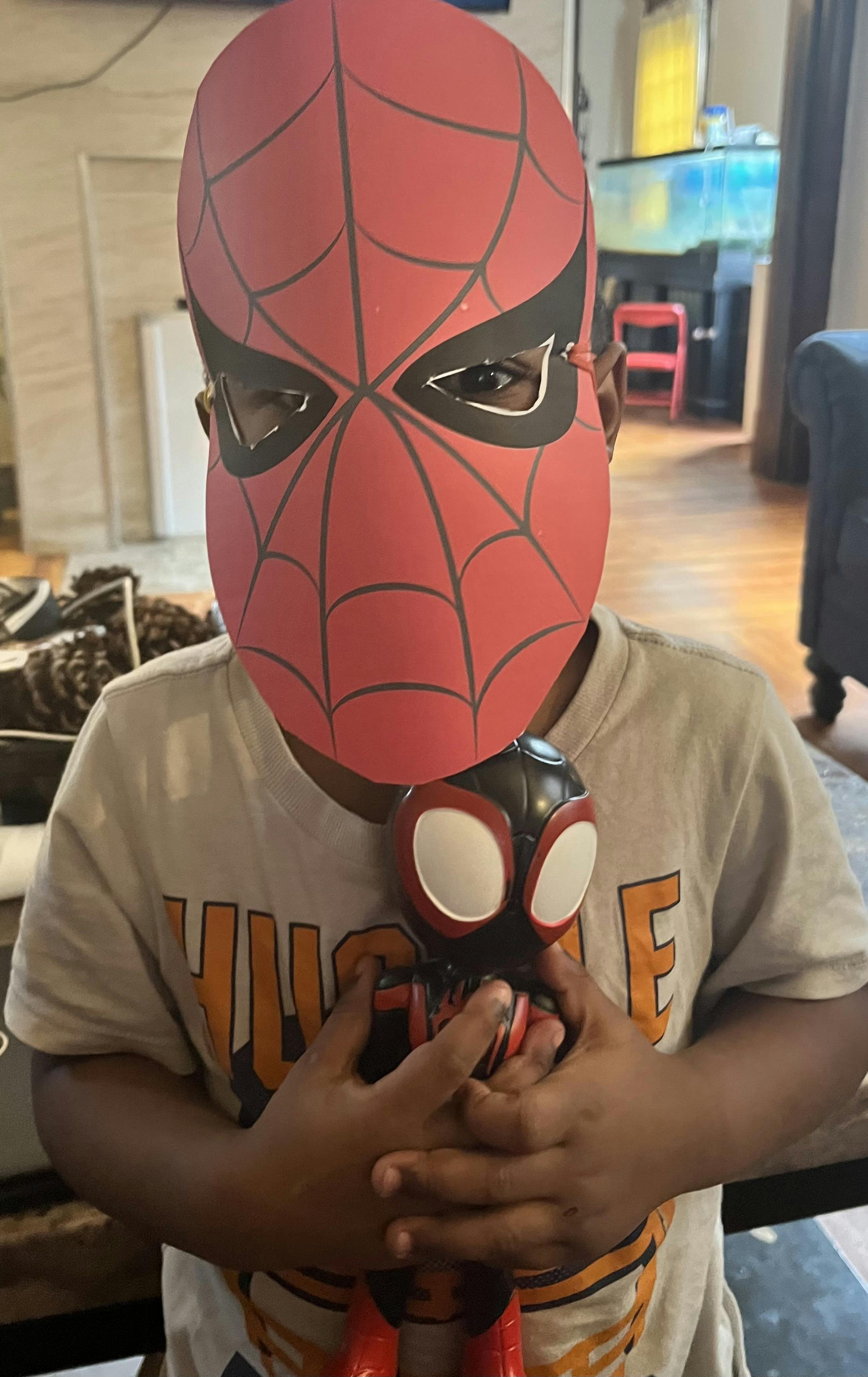 Child wearing a Spider-Man mask and holding a Spider-Man toy