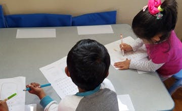 Two children drawing or writing at a table