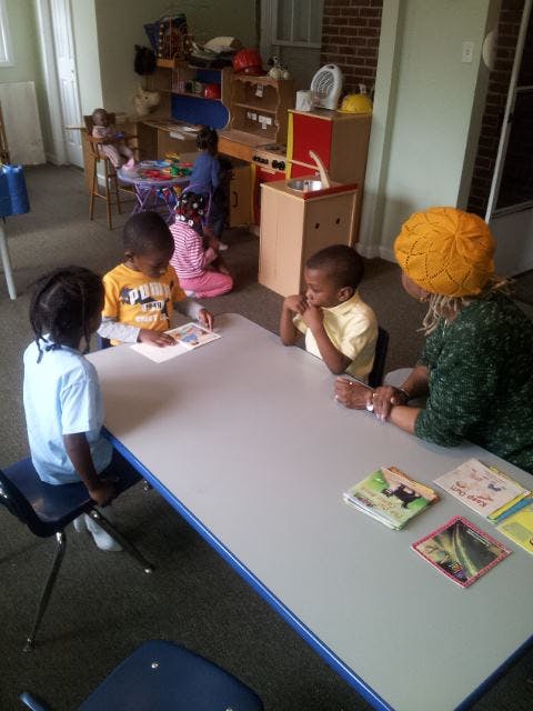 Adult and three children sitting at a table in a classroom