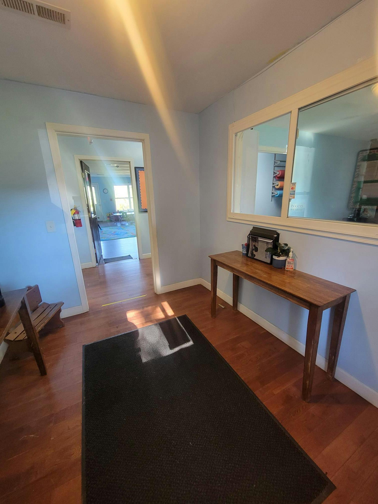 A wooden console table in a hallway with a black floor mat