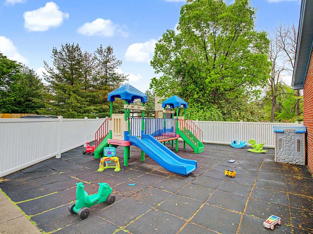 Outdoor children's playground with colorful play structures and rubber mat flooring