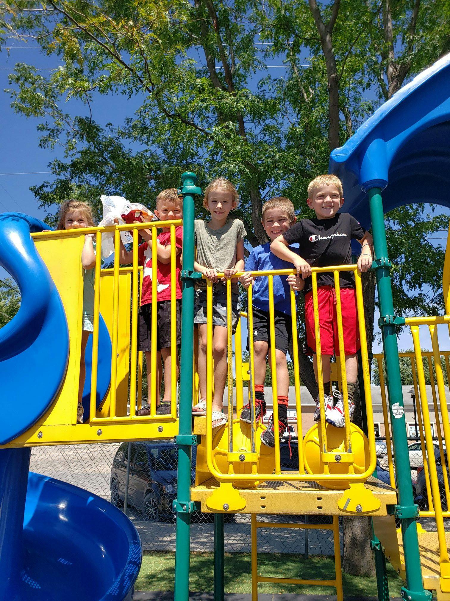 Children standing on a yellow and blue playground structure