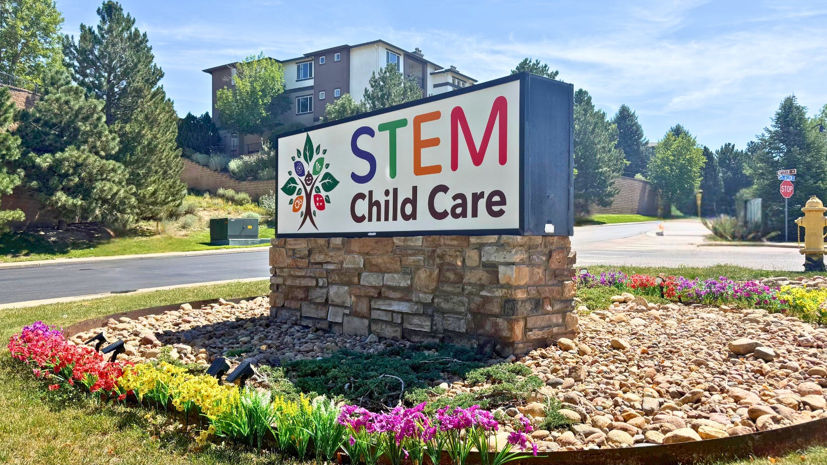 Signage for STEM Child Care placed on a stone base among flowers