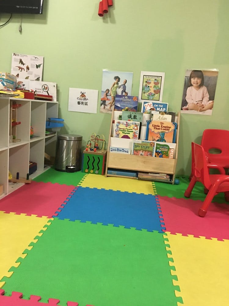 Playroom with colorful interlocking floor mats, bookshelves, and red chairs