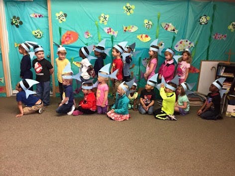 Group of children in a classroom wearing fish hats