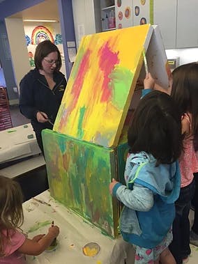 Adult and children painting a large box structure