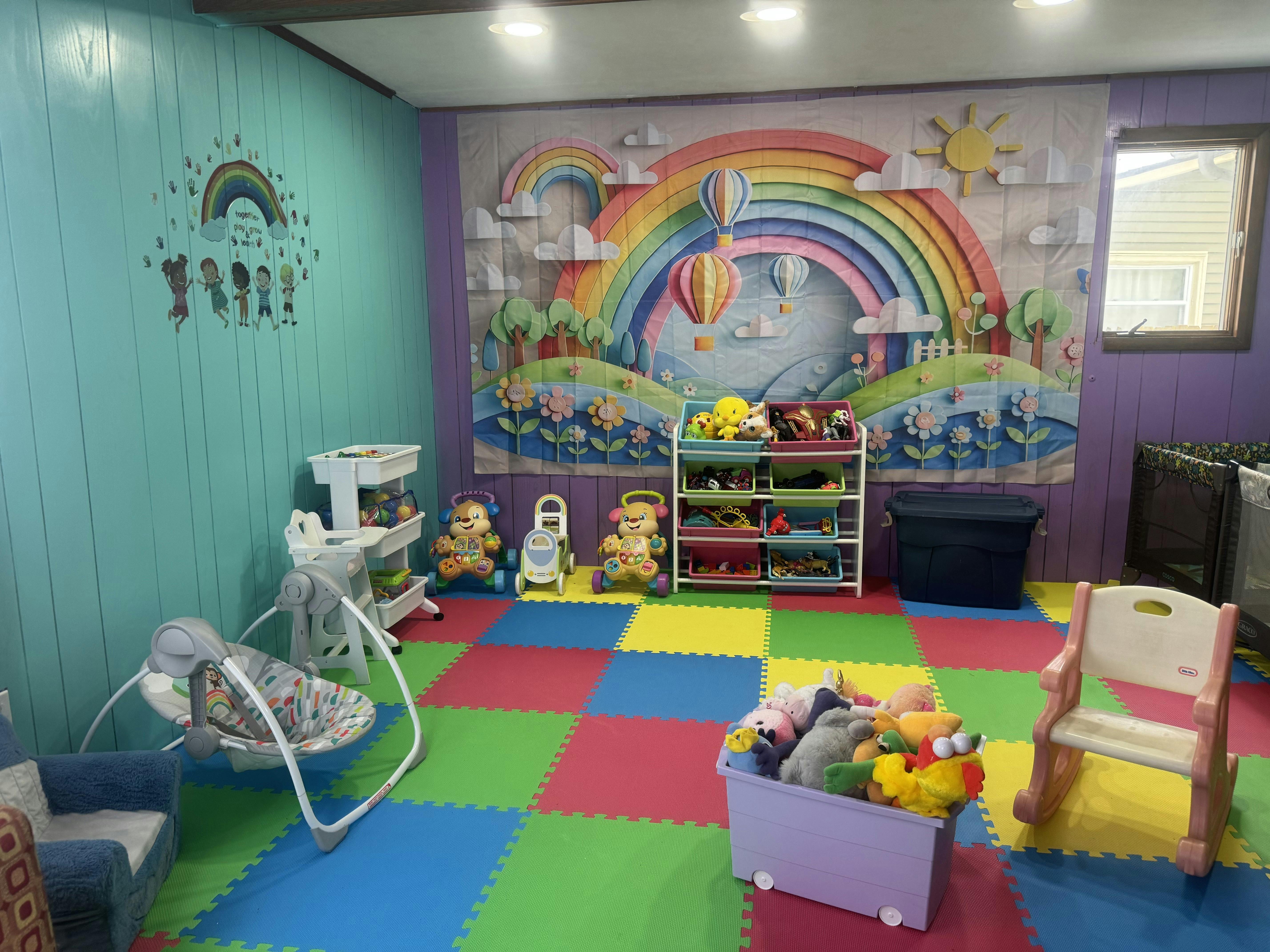 Colorful playroom with rainbow and hot air balloon wall art, toys, and padded floor