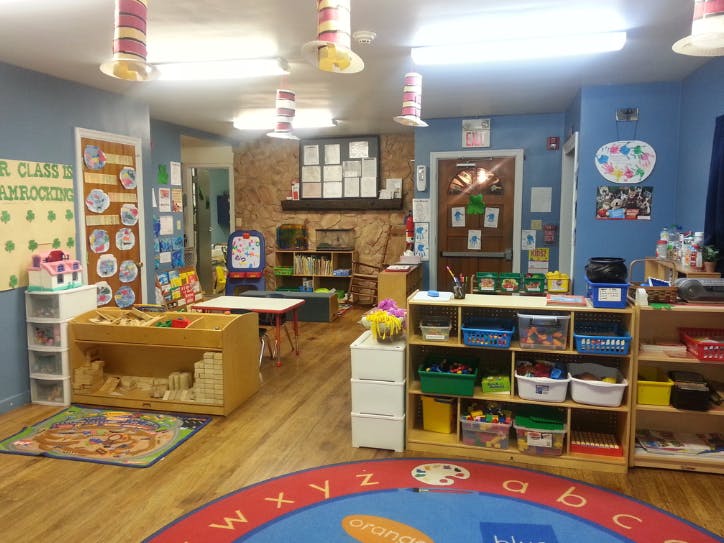 Classroom with play areas, shelves of toys, and colorful rugs