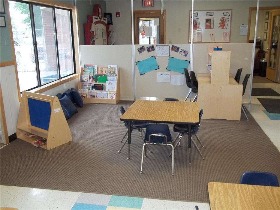 Classroom with a reading nook, tables and chairs, and partitioned study areas