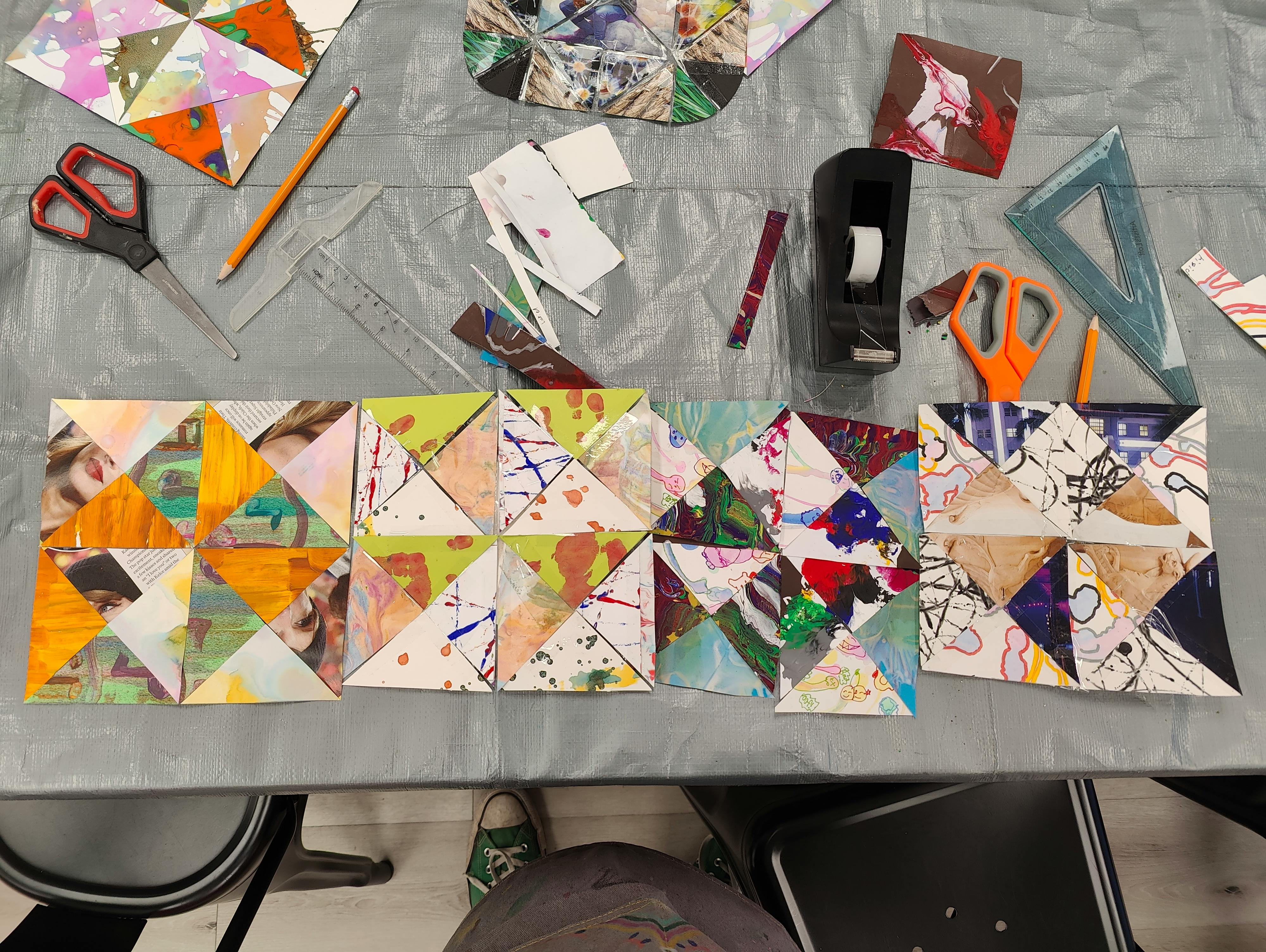 Craft supplies and patchwork art pieces on a grey table