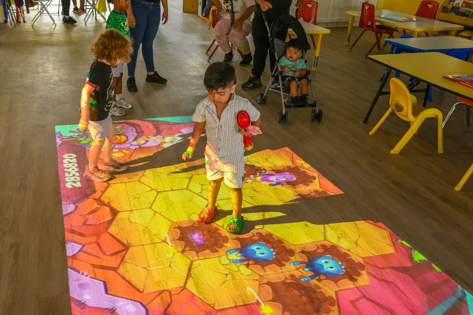 Children playing on an interactive floor projection in a room