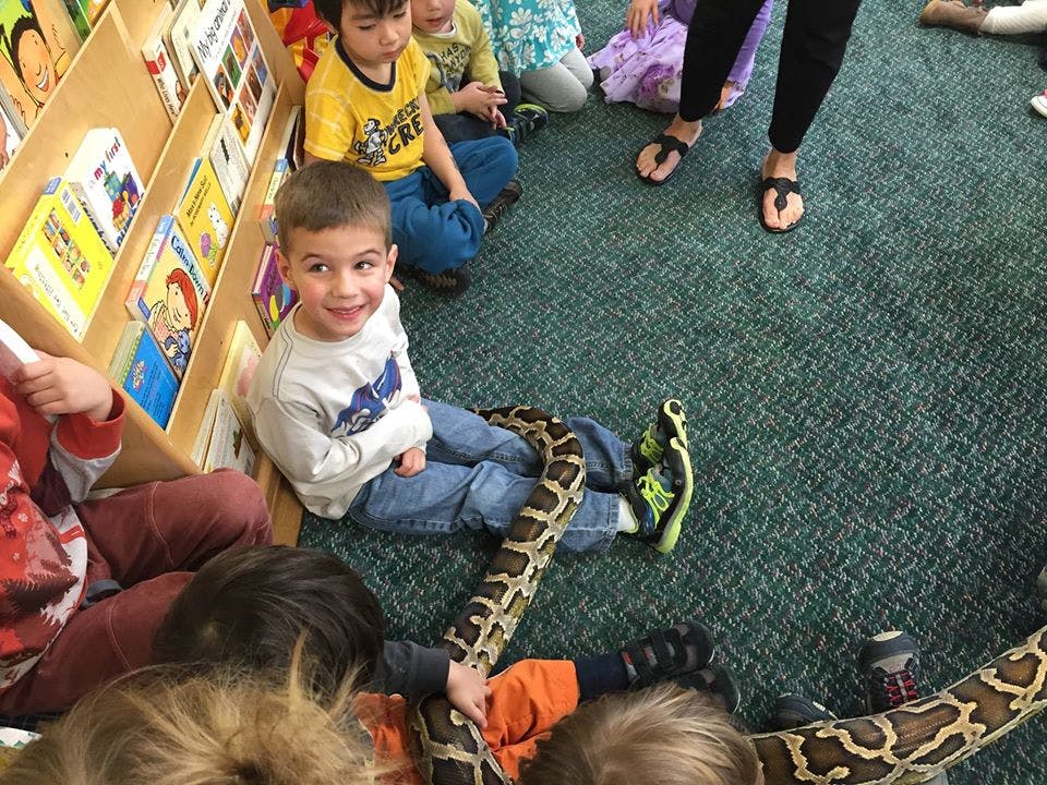 Children sitting on a carpet with a large snake