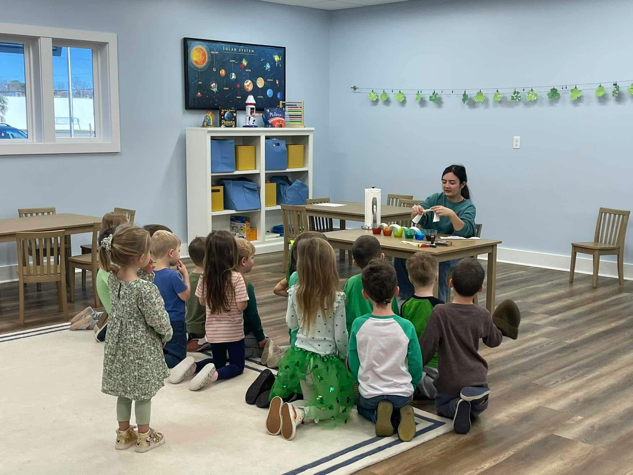 Group of children observing an adult conducting a science experiment