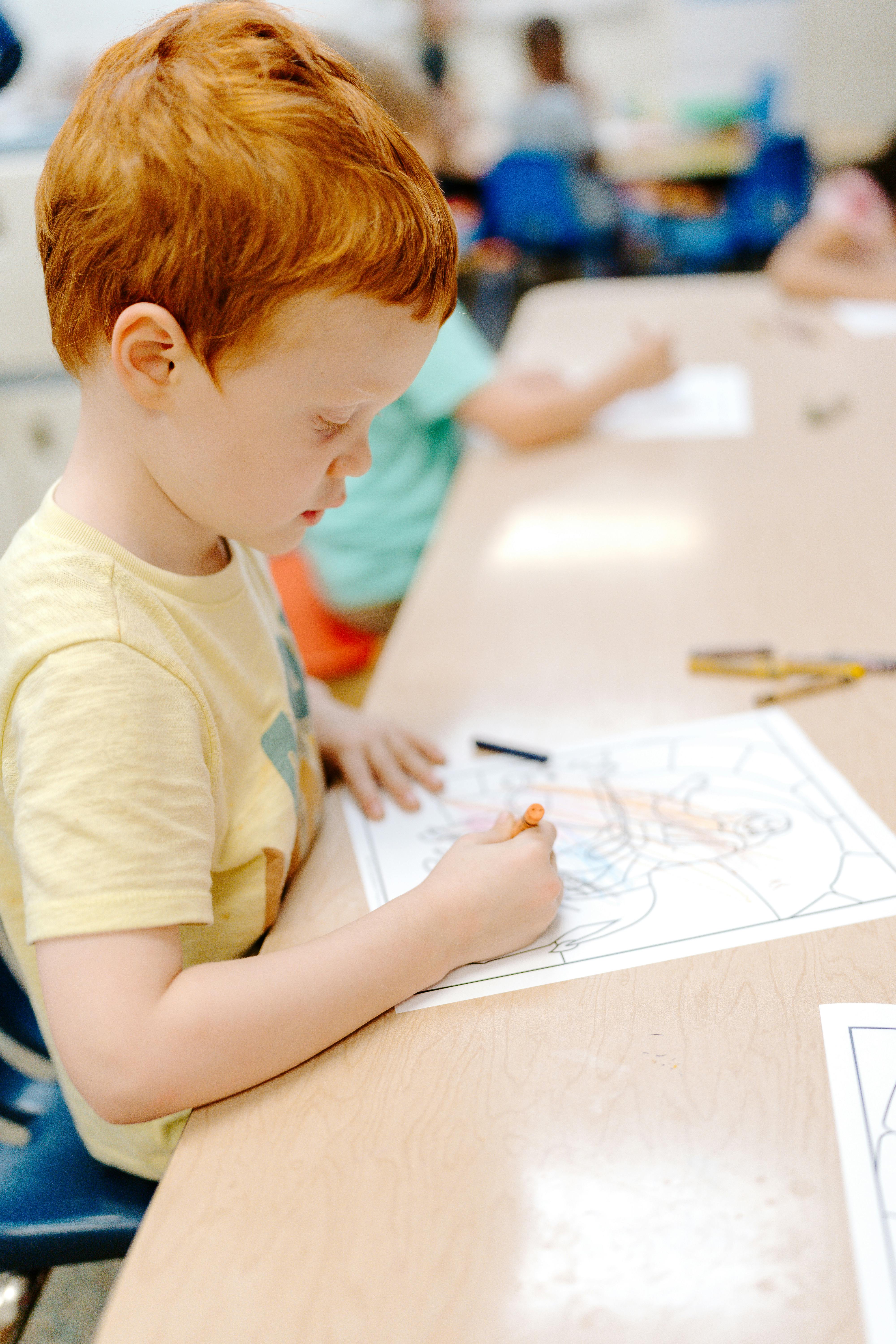 Child coloring at a table in a classroom