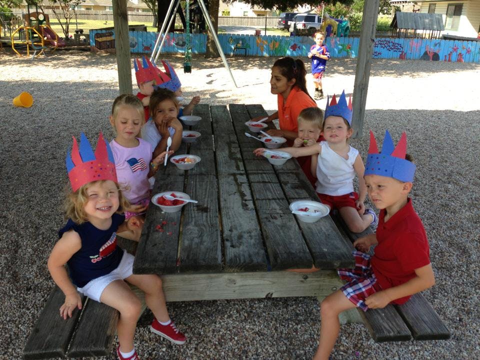 Children wearing paper crowns sitting at a picnic table with bowls