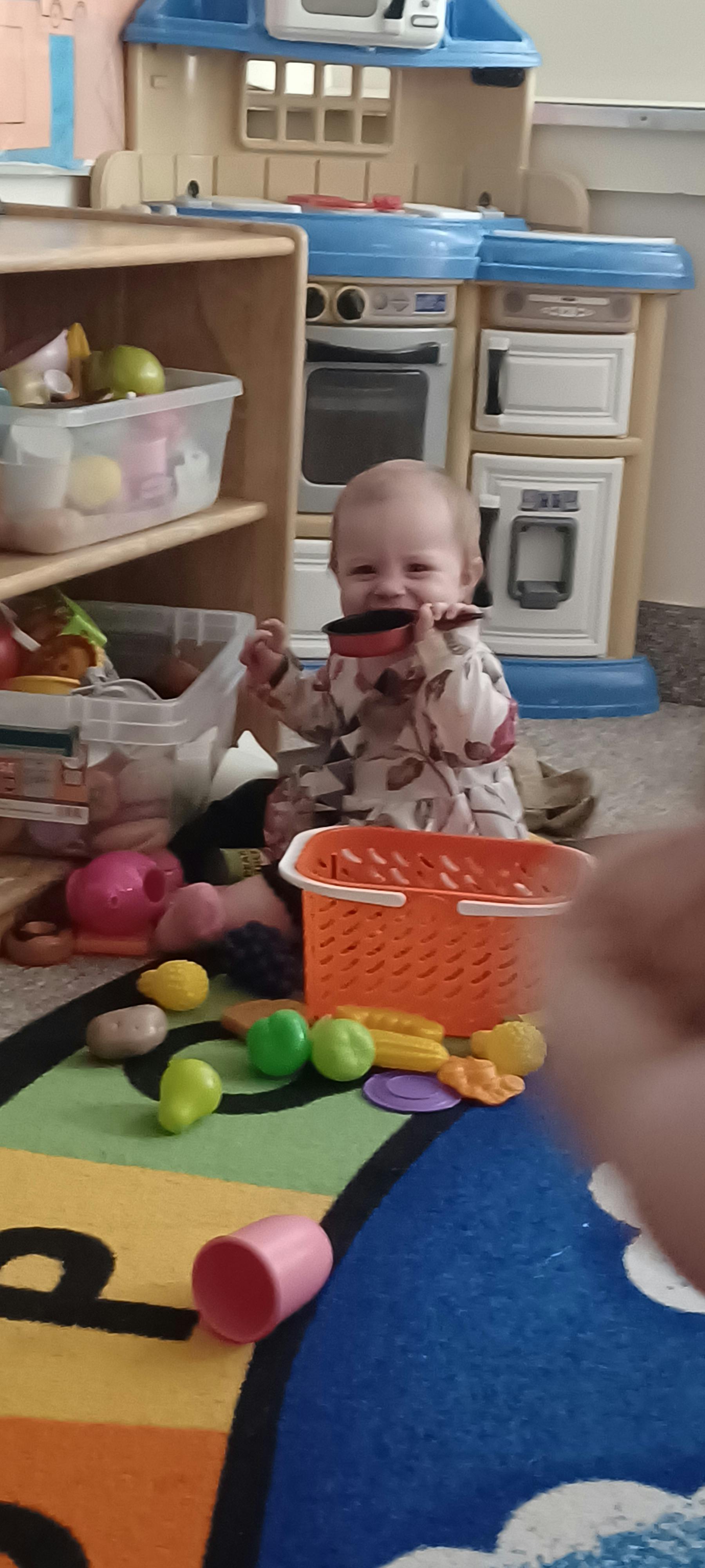 Child playing with a toy pot in a play kitchen