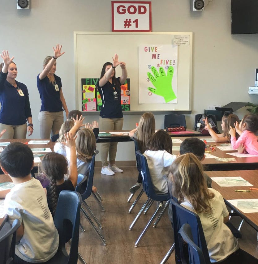 Adults and children raising hands in a classroom