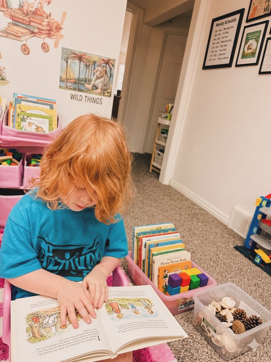 Child with red hair sitting and reading a book