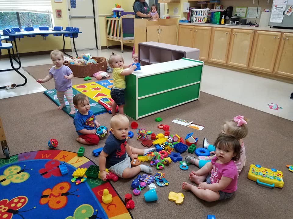 Multiple children playing with toys on the floor in a room