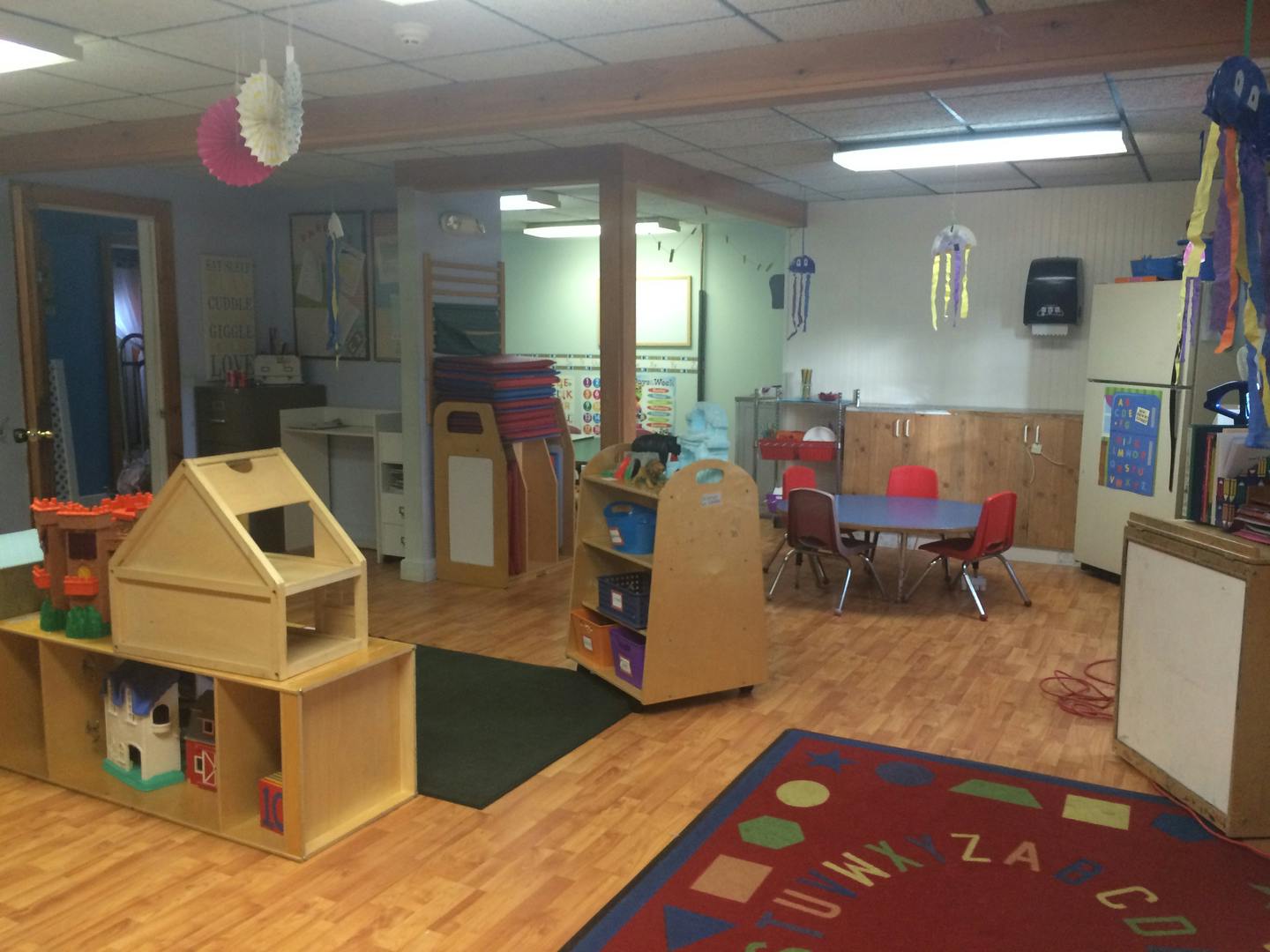 A classroom with a small table and chairs, shelves, and a playhouse