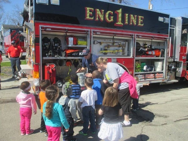 Adults and children gathered around a fire truck with "ENGINE" on its side