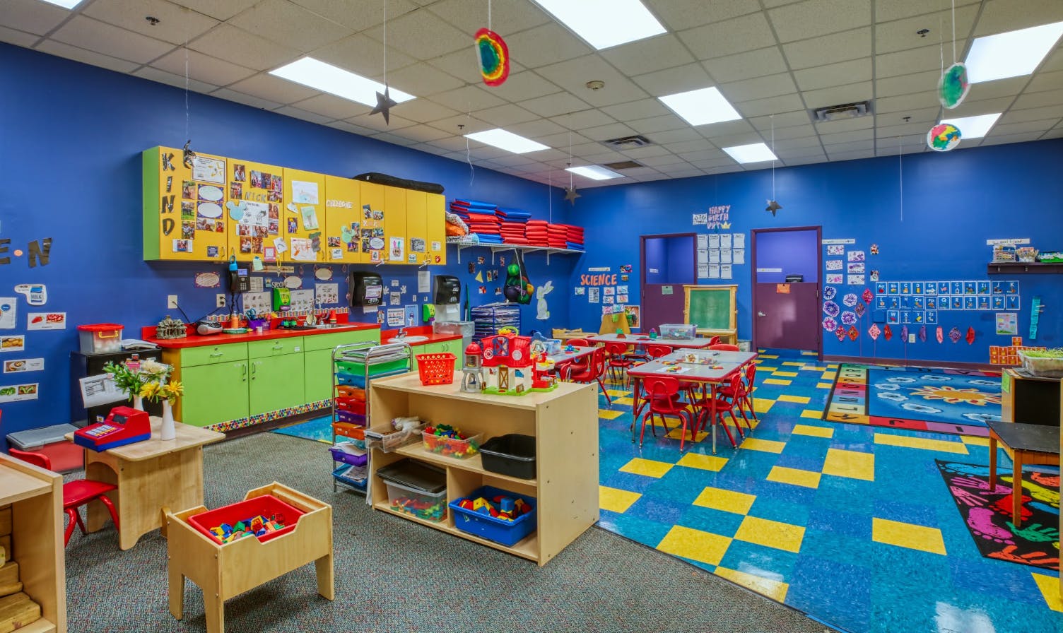 Colorful preschool classroom with blue walls, small tables, and learning materials