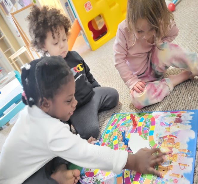 Three children playing a board game on the floor