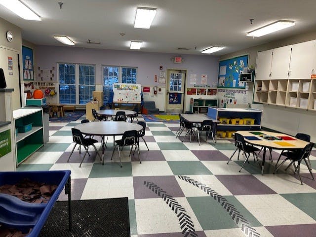 Empty children's classroom with small tables and chairs