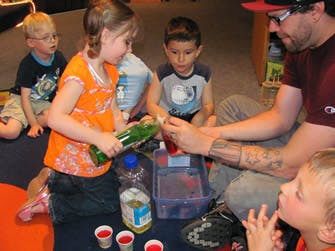 Adult and children doing an activity with bottles and cups