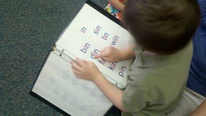 Child pointing at words in a binder