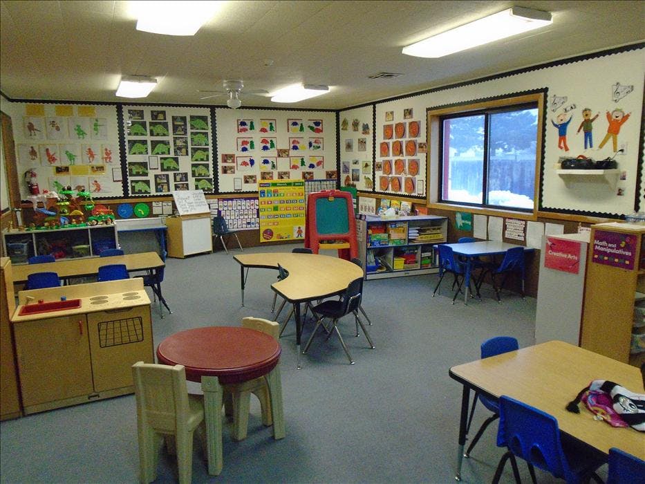 A classroom with child-sized tables and chairs, and art on the walls