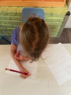 Child writing on paper with a pencil