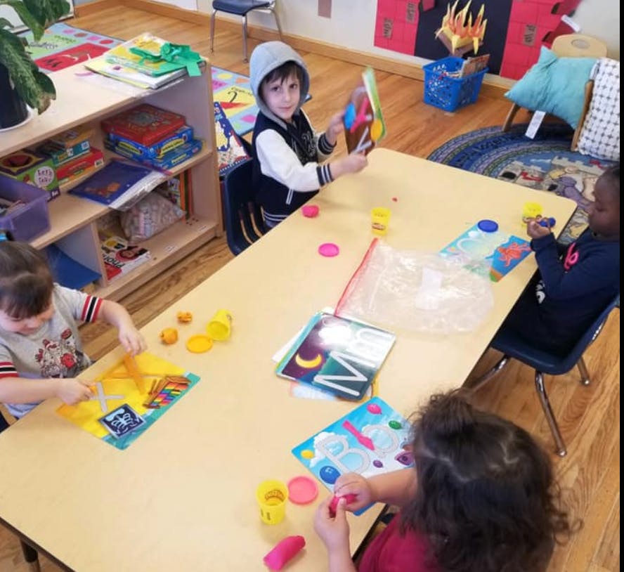 Children at a table playing with colorful objects