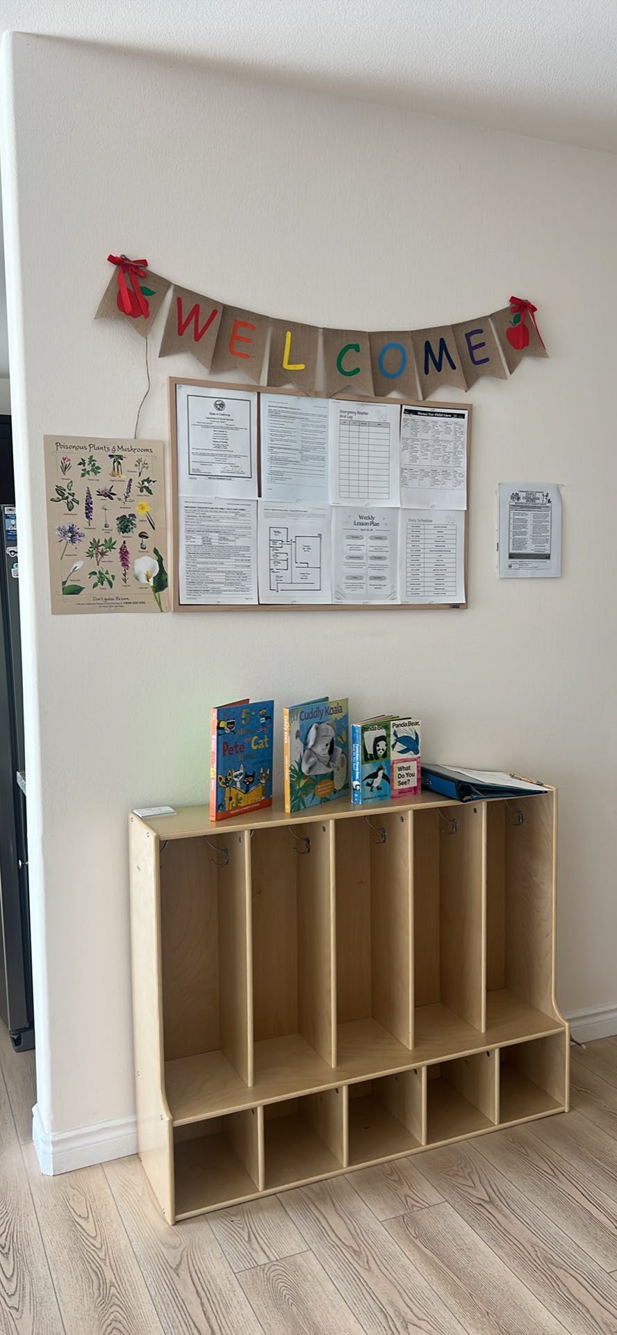 Classroom wall with a "WELCOME" banner, bulletin board, and cubby organizer