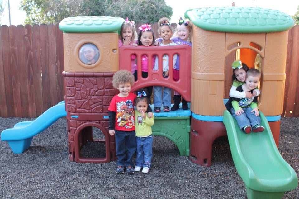 Children playing on a colorful outdoor playset with slides