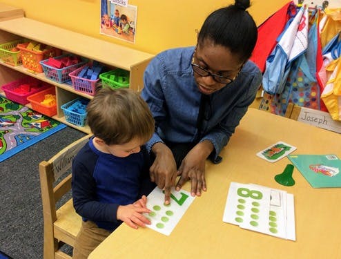 Person and child pointing at number cards on a table