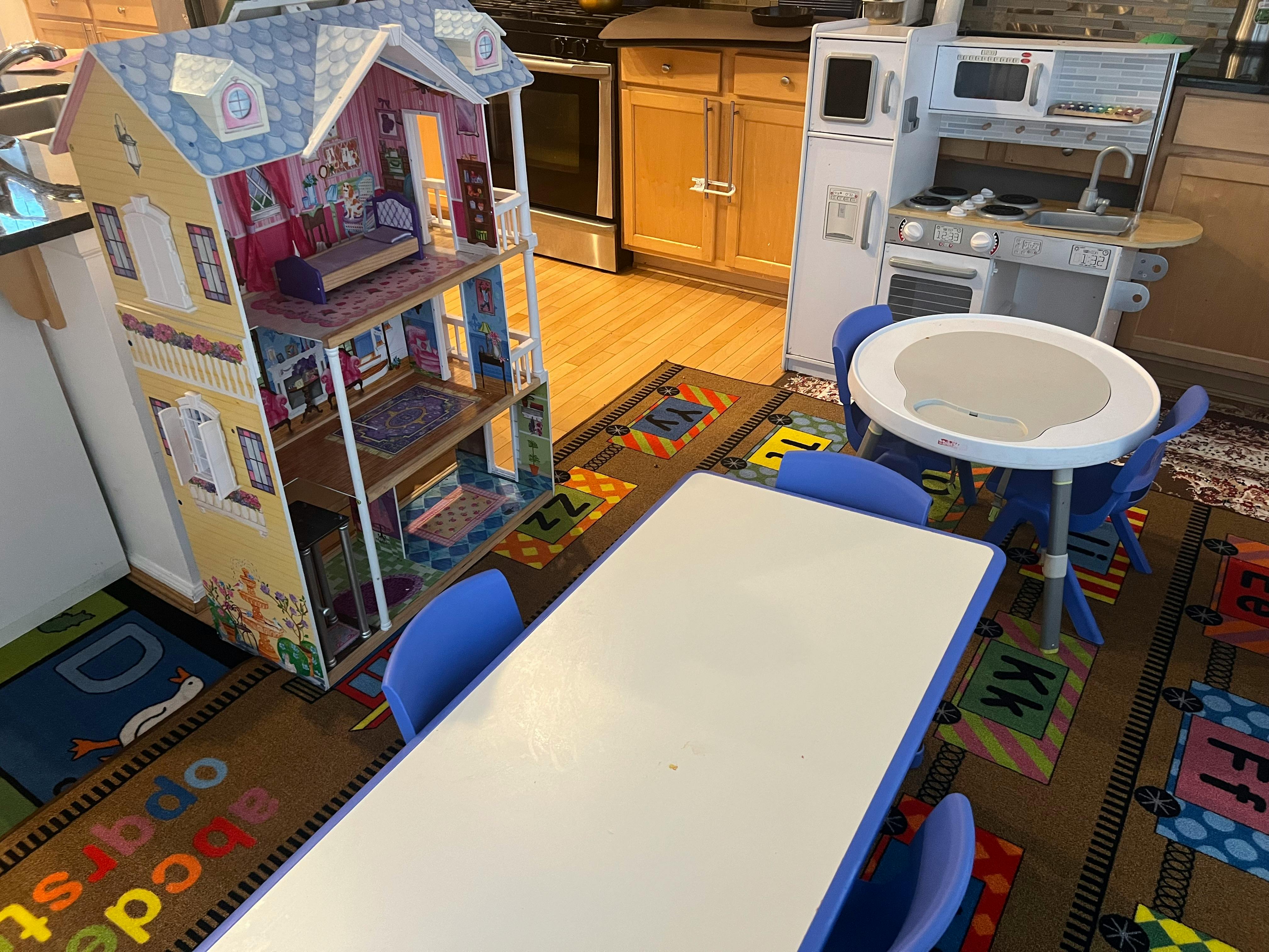 Dollhouse, play kitchen, and children's tables with chairs