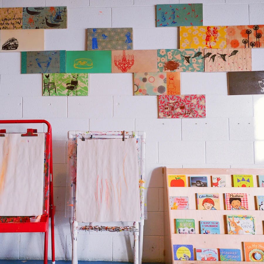 Art studio with easels, a bookshelf, and colorful art on the wall
